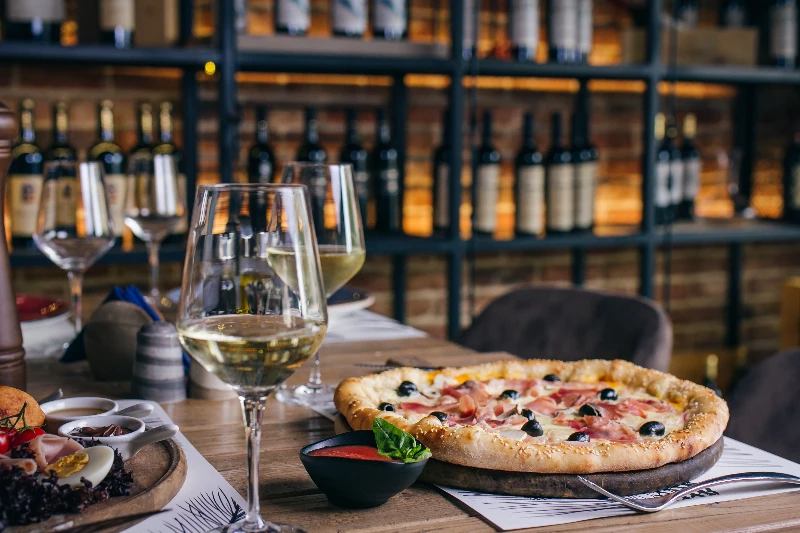 Pizza with prosciutto and olives with wince in restaurant